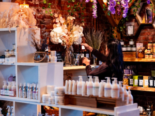 Artisan Skincare & Wellness Products | Founders’ Food Hall & Market Charlottetown Woman browsing artisan skincare and wellness products at a local vendor inside Founders’ Food Hall & Market in Charlottetown, PEI.