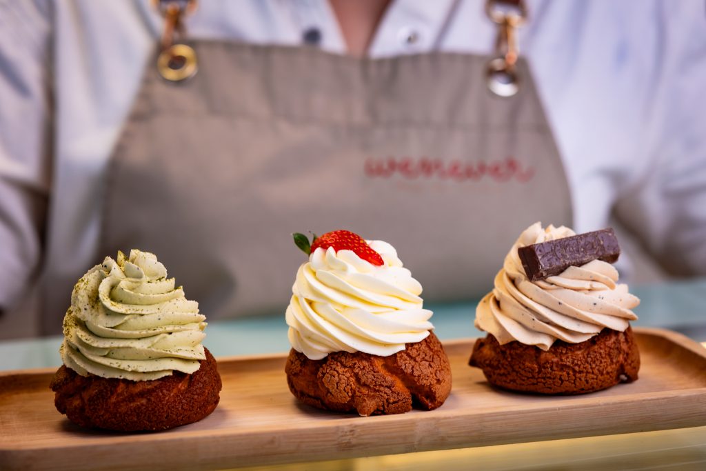 Gourmet Cream Puffs | Founders’ Food Hall & Market Desserts Charlottetown Trio of gourmet cream puffs topped with matcha, strawberry, and chocolate displayed at Founders’ Food Hall & Market in Charlottetown, PEI.