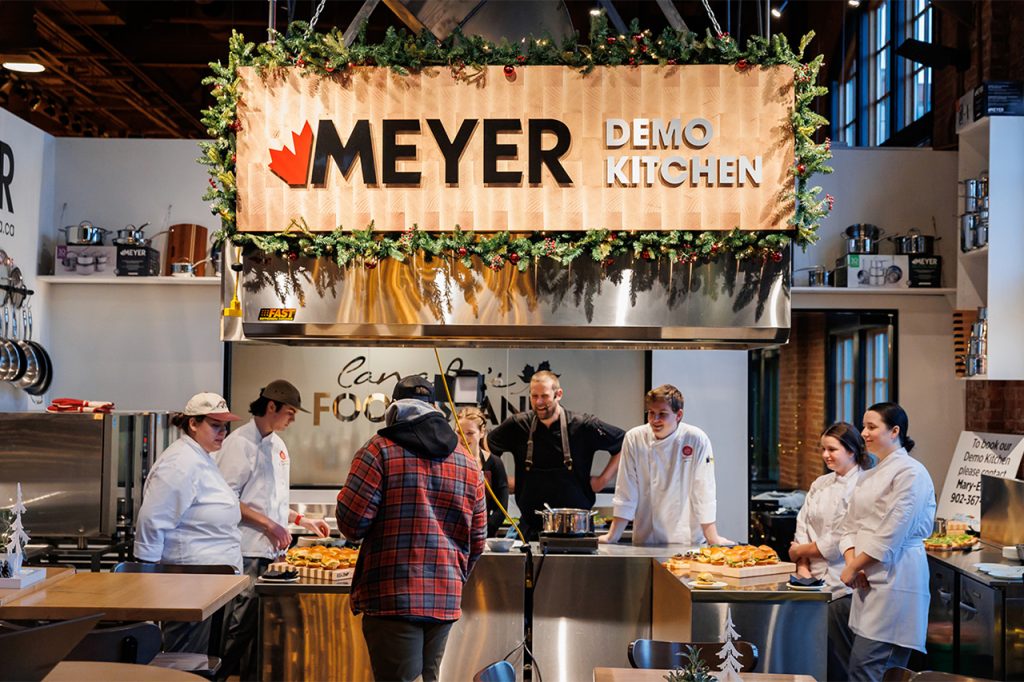 Chefs presenting food samples during a live cooking demonstration at the Meyer Demo Kitchen