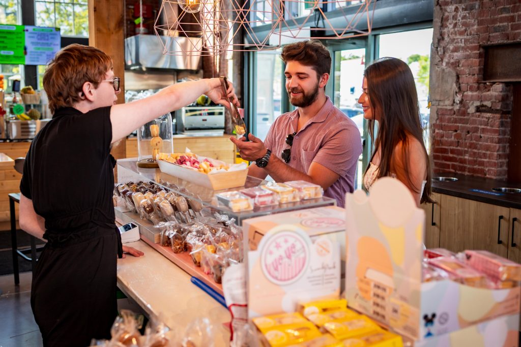 Couple sampling Yo Yo Cookies at a dessert counter inside Founders’ Food Hall & Market.