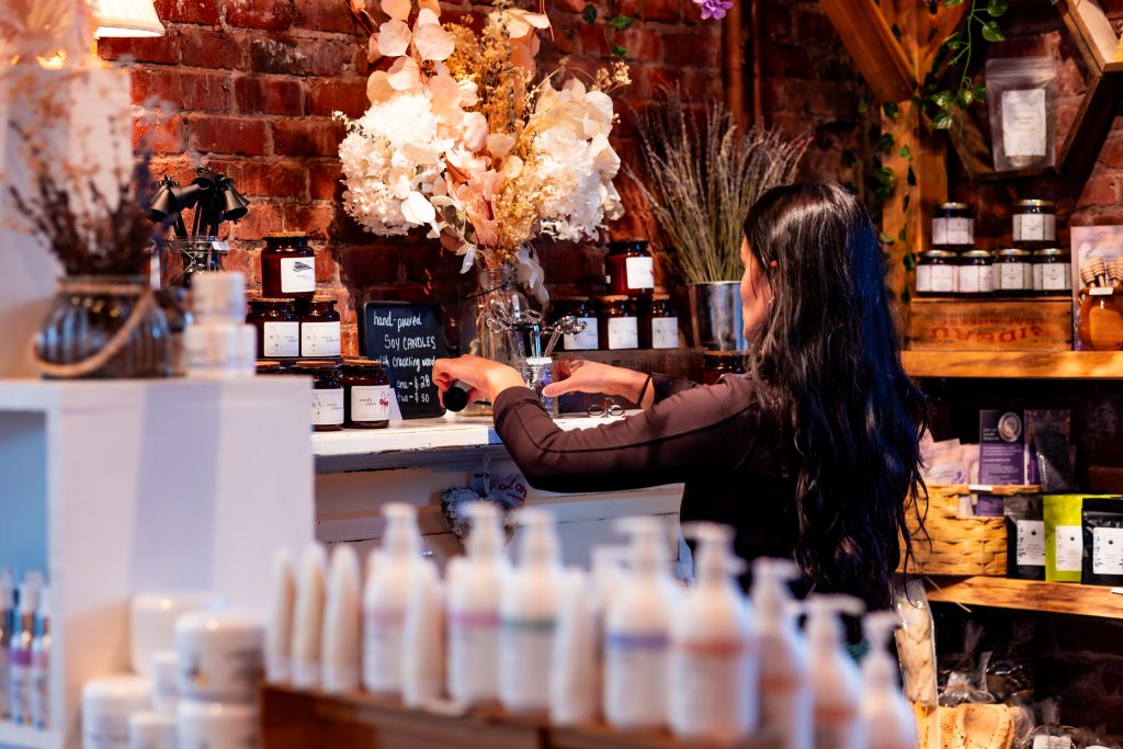 Woman arranging hand-poured soy candles on display at Founders’ Food Hall & Market in Charlottetown, PEI