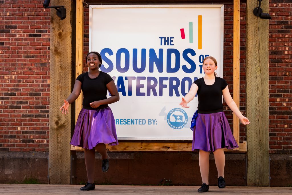 Two young dancers perform on the Sounds of the Waterfront stage at Founders' Food Hall & Market during a free live music and entertainment event in Charlottetown, PEI.